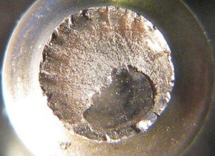 Detail lomové plochy hřídelky - Detail lomové plochy je šestkrát zvětšený.Trhliny postupují z povrchu hřídelky k jejímu středu.Po podrobném prozkoumání bylo zjištěno, že příčinou praskńutí hřídelky je únavový lom.turbínového kola  