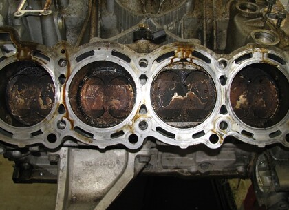 Po sejmutí hlav válců se ukáže skutečný stav pístů a spalovacích prostorů - Na druhém pístu z pravé strany (v horní úvrati) jsou patrné dvě protilehlé lesklé plošky. Právě zde narážel píst do hlavy válců, čímž způsoboval tak hlasité klepání.  